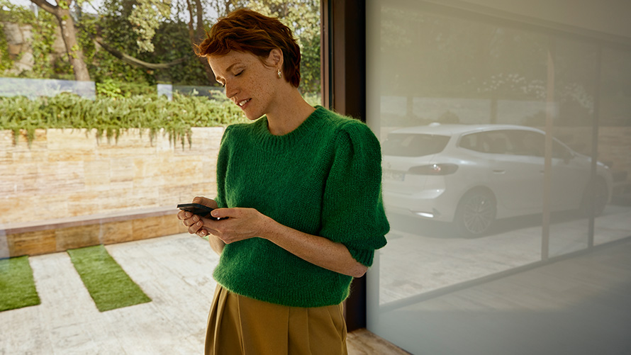 BMW Service Inclusive žena drži pametni telefon Žena drži pametni telefon BMW Service Inclusive