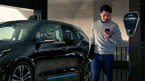 Čovek pored BMW-a i3 na stanici za punjenje BMW Finansijske usluge čovek pored BMW-a i3 ispred stanice za punjenje