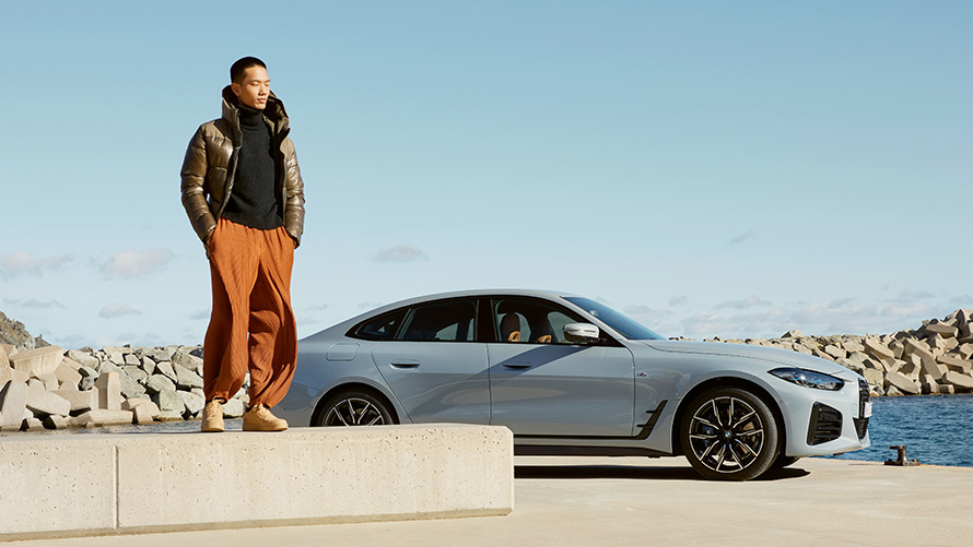 BMW Service Inclusive čovek ispred BMW-a i4 na obali