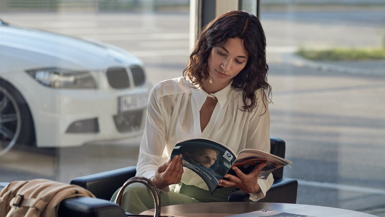 BMW Garancija salona BMW Repair and Care (Popravka i nega) žena sedi sa BMW-ovim katalogom u ruci