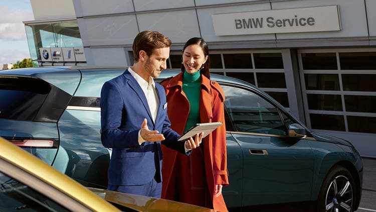 BMW Service Muškarac i žena ispred BMW iX-a kod BMW-vog servisnog partnera