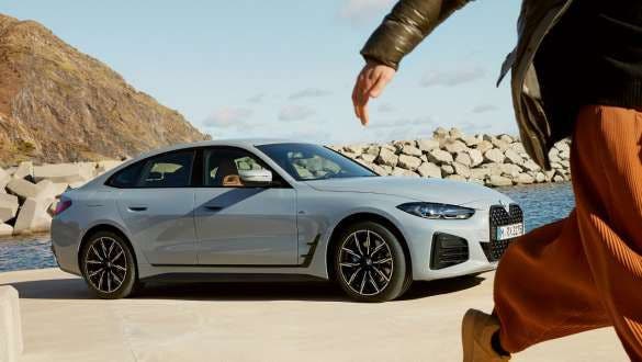 BMW Service Inclusive žena prolazi pored BMW-a i4 na obali